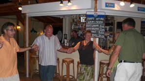 A bar area with stools and a chalkboard menu listing drinks and prices. - Sunshine Garden (Hersonissos)