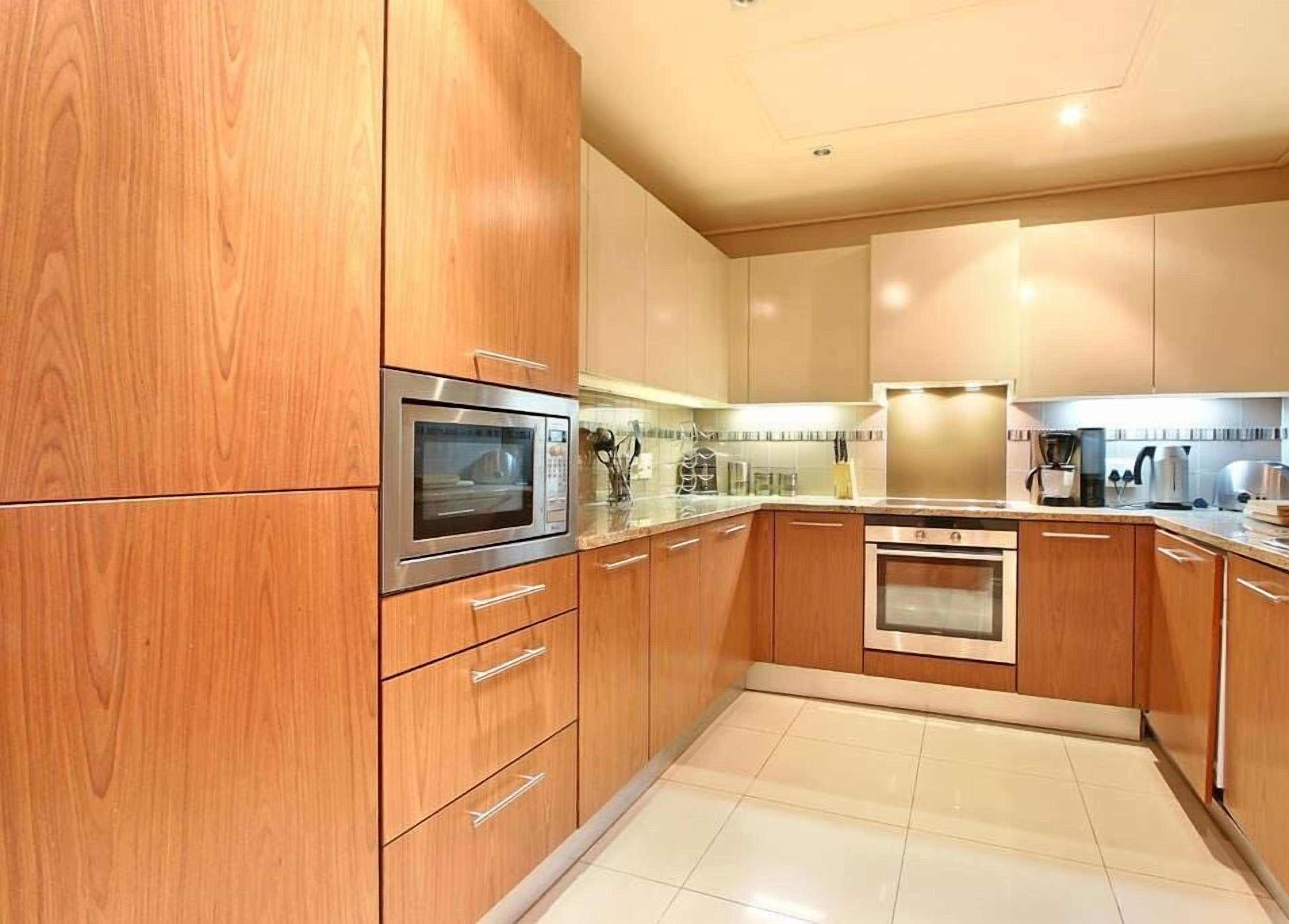 Une cuisine moderne avec des meubles en bois, des appareils en acier inoxydable et un sol carrelé.