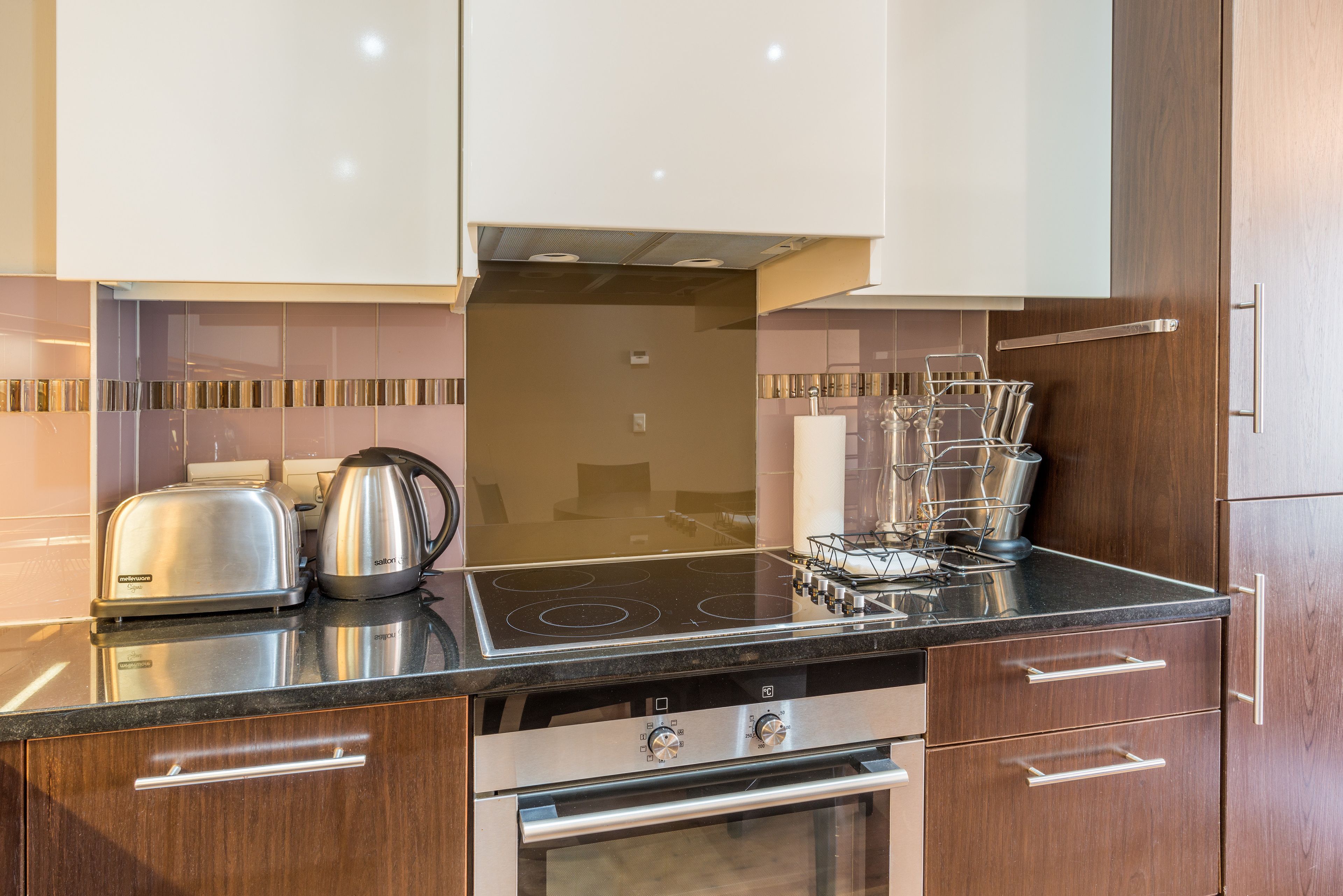 A modern kitchen with stainless steel appliances, wooden cabinets, and a black countertop.