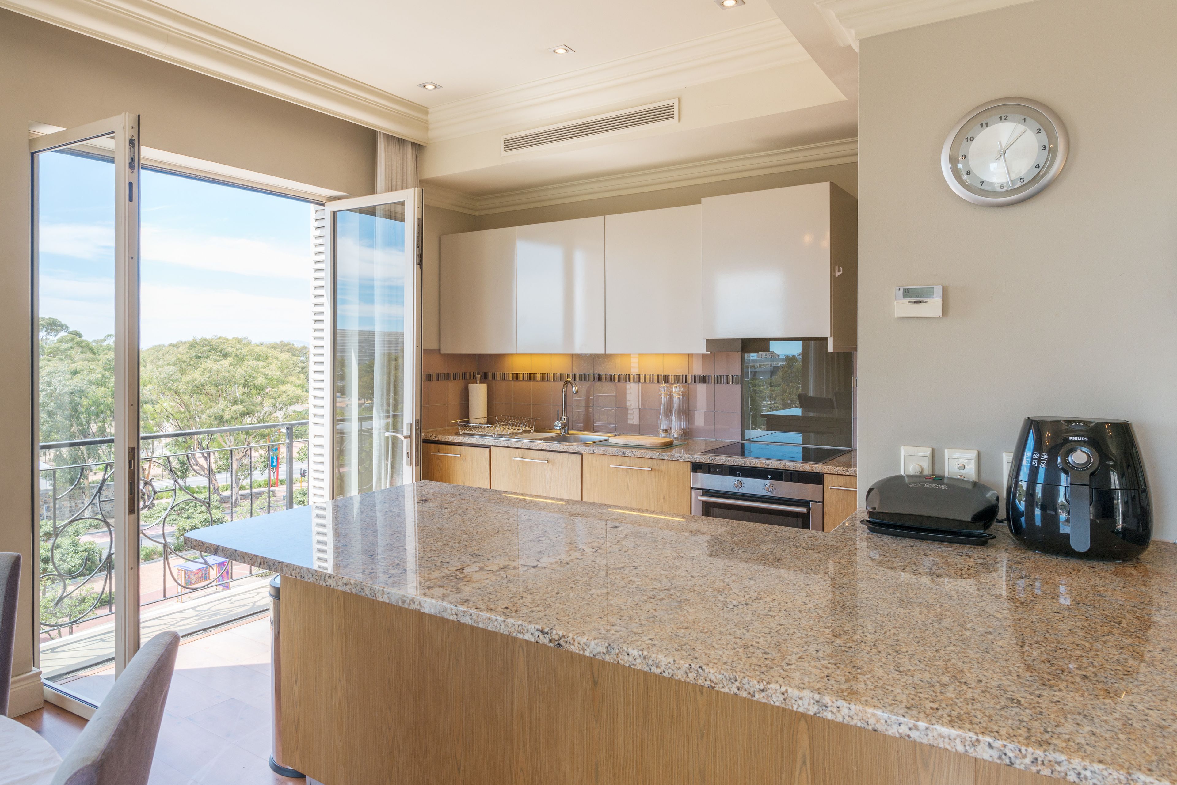 A modern kitchen with a granite countertop, stainless steel appliances, and a view of the outdoors.