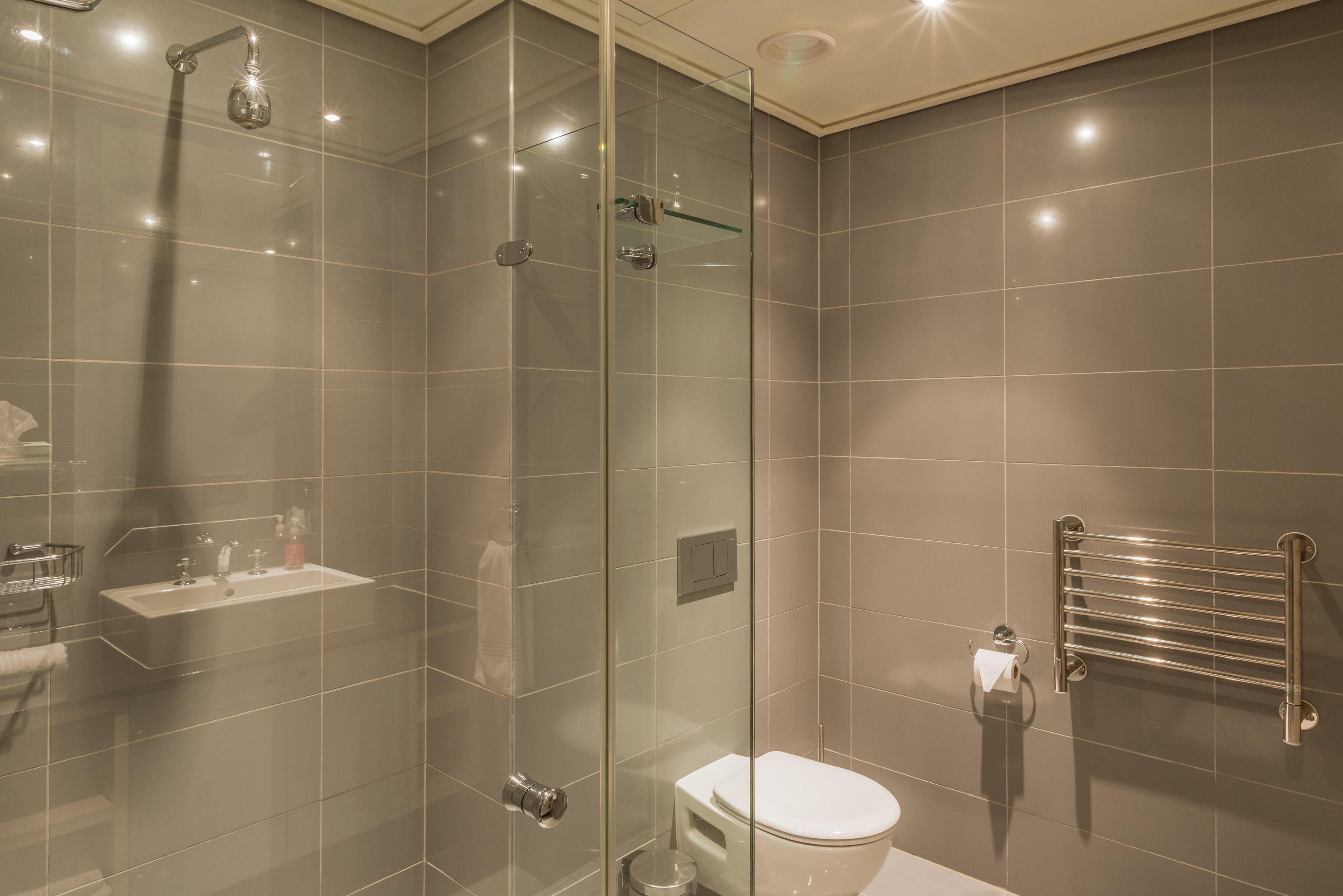 A modern bathroom with a glass-enclosed shower, a toilet, and a glass sink.