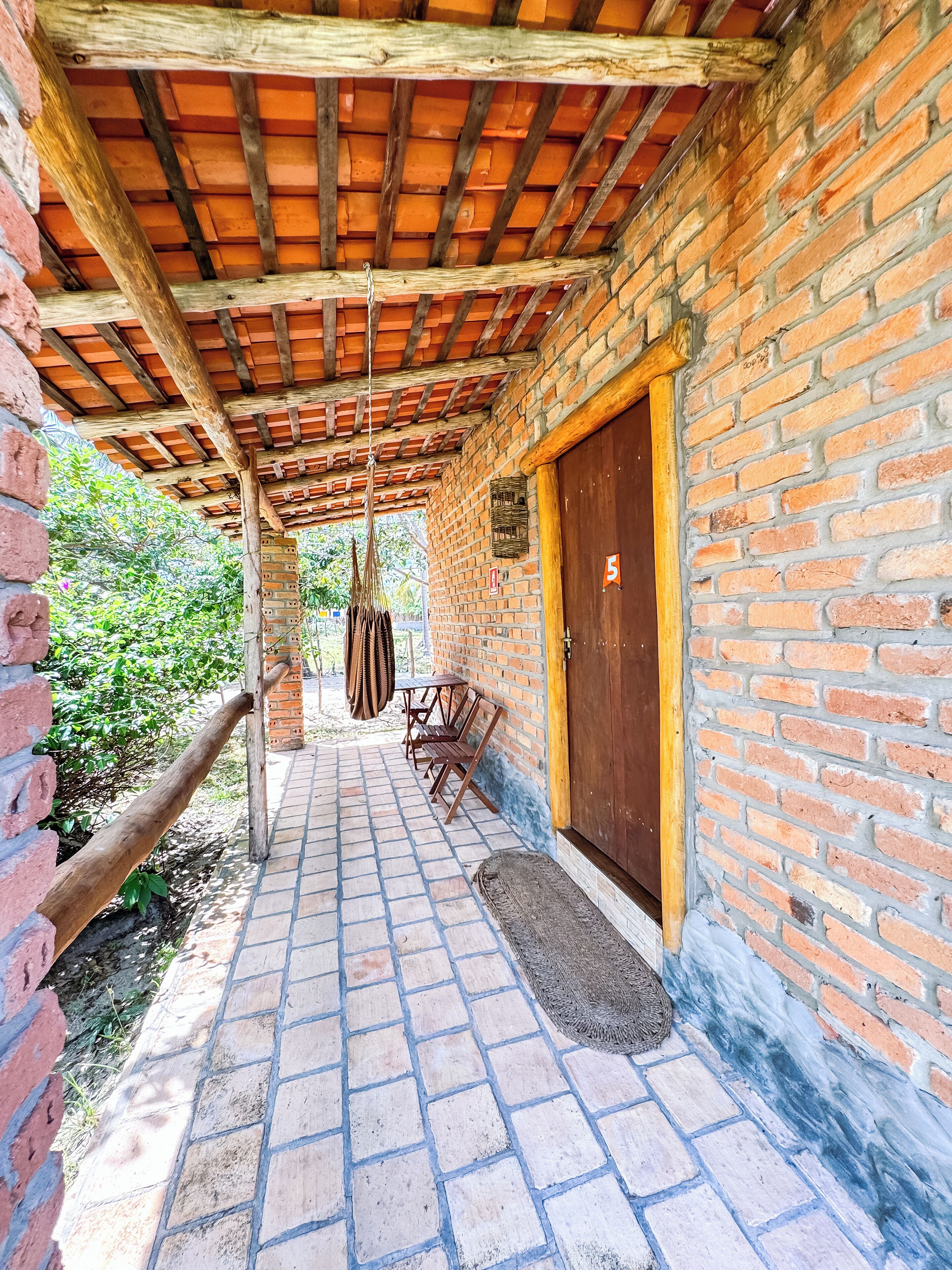 Un espacio al aire libre cubierto con pared de ladrillo, vigas de madera y una puerta con el número 5.