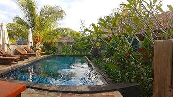 Una piscina al aire libre, sillones reclinables de piscina