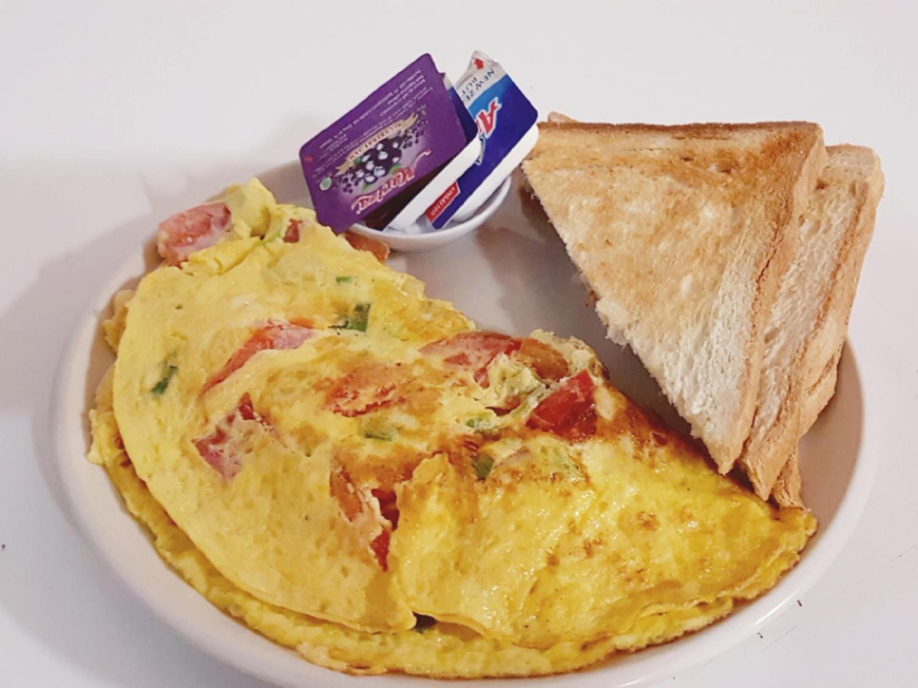 A plate with an omelette, toast, and a small container of butter.