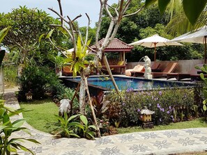 A pool area with lounge chairs, a small gazebo, and decorative statues. - The Akah Cottage (Lembongan Island)