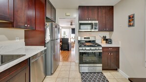 A modern kitchen with stainless steel appliances, wooden cabinets, and a tiled floor. - Pacific Beach Apartment: Walk to Beach & Pier! (San Diego)
