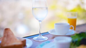 Una mesa con un vaso de agua, una taza y un vaso de zumo de naranja.