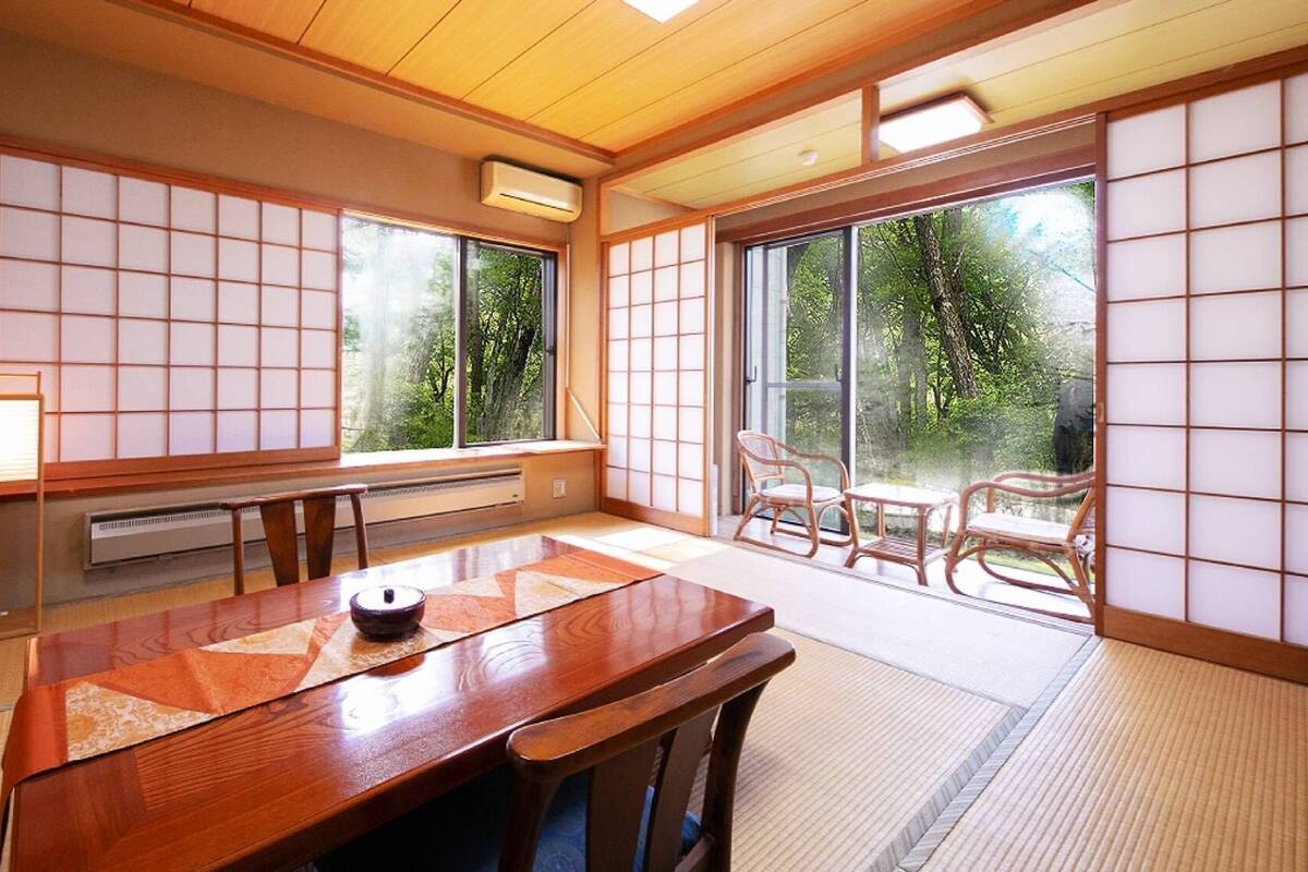 A traditional Japanese room with tatami flooring, a wooden table, and sliding doors.