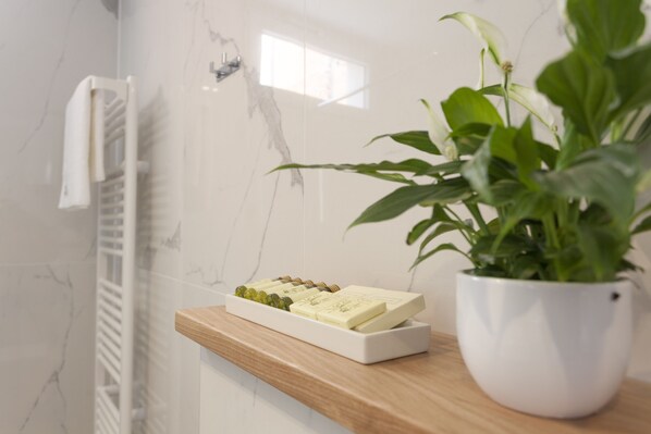 A bathroom with a marble wall, a wooden shelf with a soap dish, and a potted plant. - Luxury Penthouse on Main Square w/ Rooftop Terrace & Sea Views (Makarska)