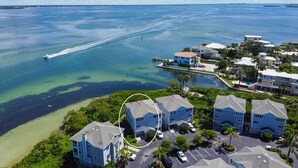 An aerial view of a coastal residential area with houses, a marina, and clear blue waters. - Cedars East Bayview Tennis & Pool Unit 822 by RVA (Longboat Key)