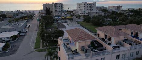 Zona residencial costera con edificios de varios pisos, una calle y vista al mar al atardecer.