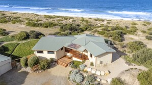 A coastal house with a large deck, a covered patio, and a view of the ocean. - Peace & Plenty - beachfront hideaway with an indoor heated pool (Dolphin Sands)