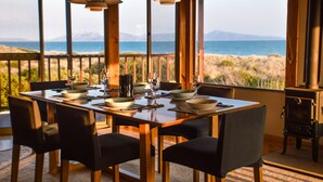 A dining area with a table set for four, large windows offering a view of the sea and mountains. - Peace & Plenty - beachfront hideaway with an indoor heated pool (Dolphin Sands)