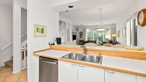 Een moderne keuken met een roestvrijstalen spoelbak, een houten aanrecht en witte kastjes.
