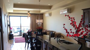 A modern kitchen with a long counter, bar stools, and a decorative red tree. - New Condo Copala/Quivira Golf Club (Cabo San Lucas)