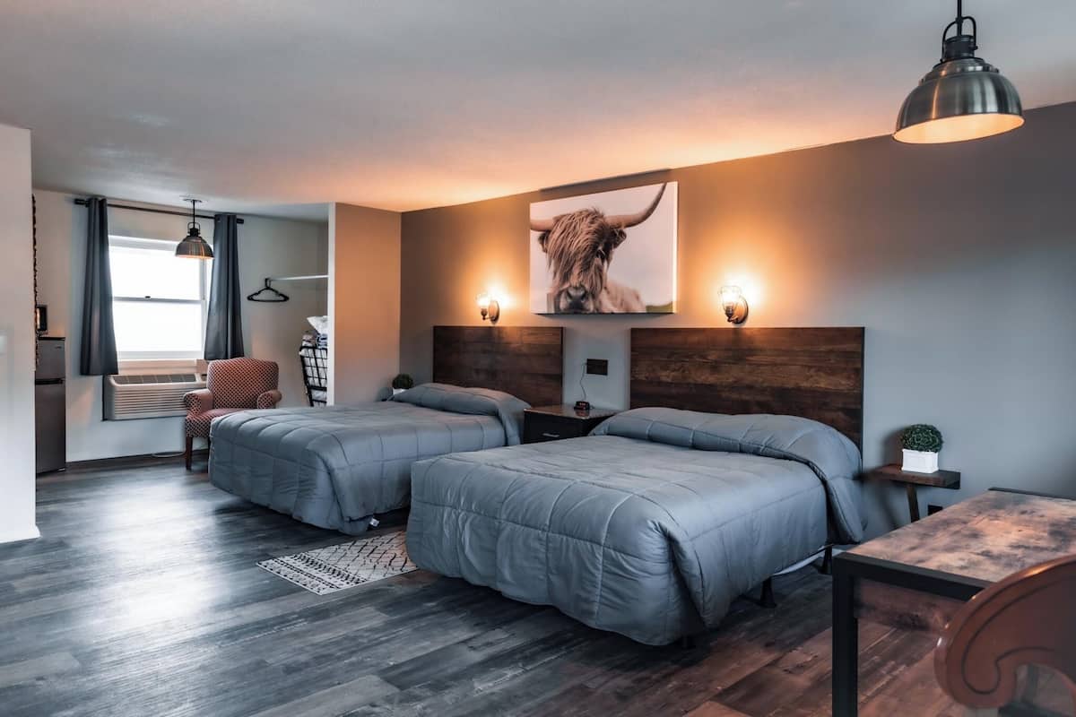 Een moderne slaapkamer met twee bedden, een houten hoofdbord, een tafeltje en een hanglamp.