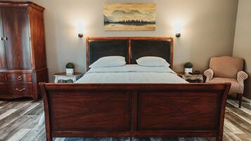 A bedroom with a wooden bed, a nightstand, a decorative lamp, a chair, and a painting on the wall.