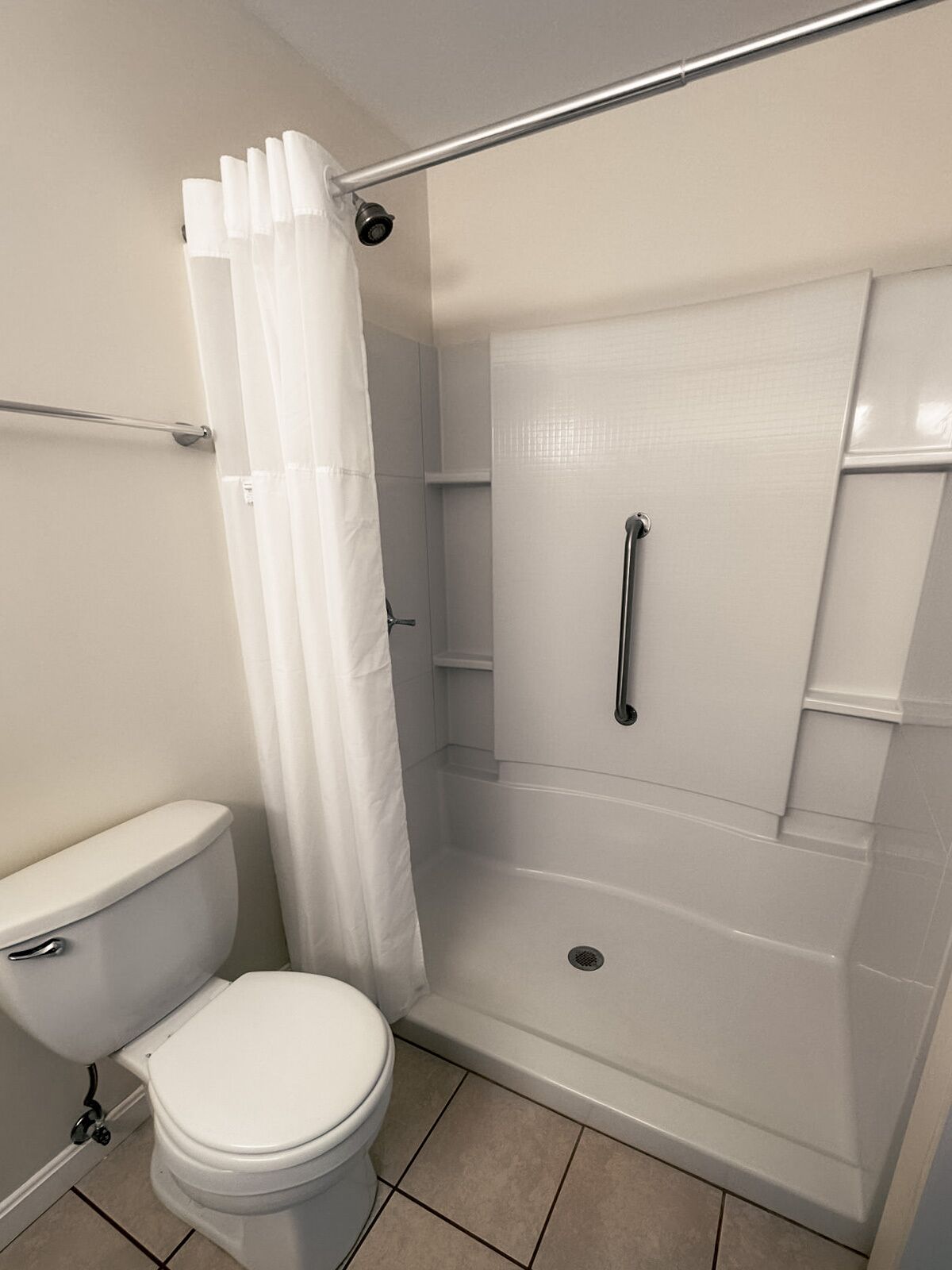 Une salle de bain avec des toilettes, une douche dotée d’une porte en verre et d’un rideau.