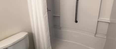 A bathroom with a toilet, a shower with a glass door, and a curtain.