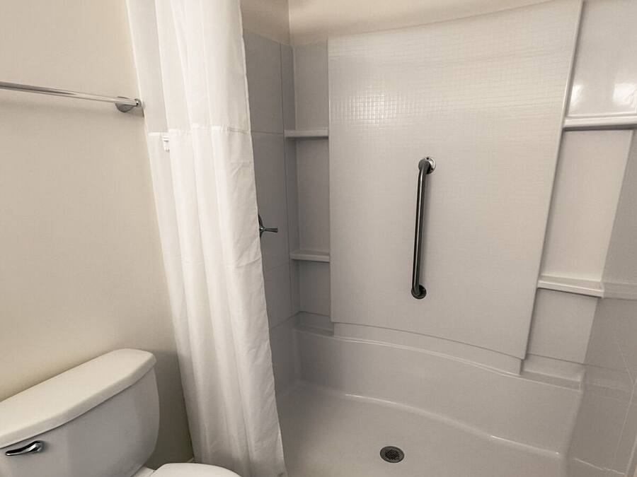 Une salle de bain avec des toilettes, une douche dotée d’une porte en verre et d’un rideau.