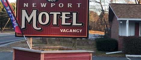 A motel sign with '467 Newport' and 'Motel' written on it, and a 'VAGANZY' label.