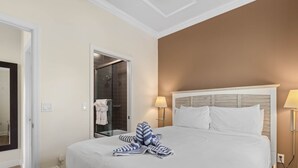 Une chambre d’hôtel comprenant un lit, une cabine de douche en verre, un miroir et deux lampes de chevet.