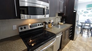 A modern kitchen with stainless steel appliances, a built-in oven, and a dishwasher. - Relax & Unwind – 1BR Beach Club Siesta Key 110D RVA (Sarasota)