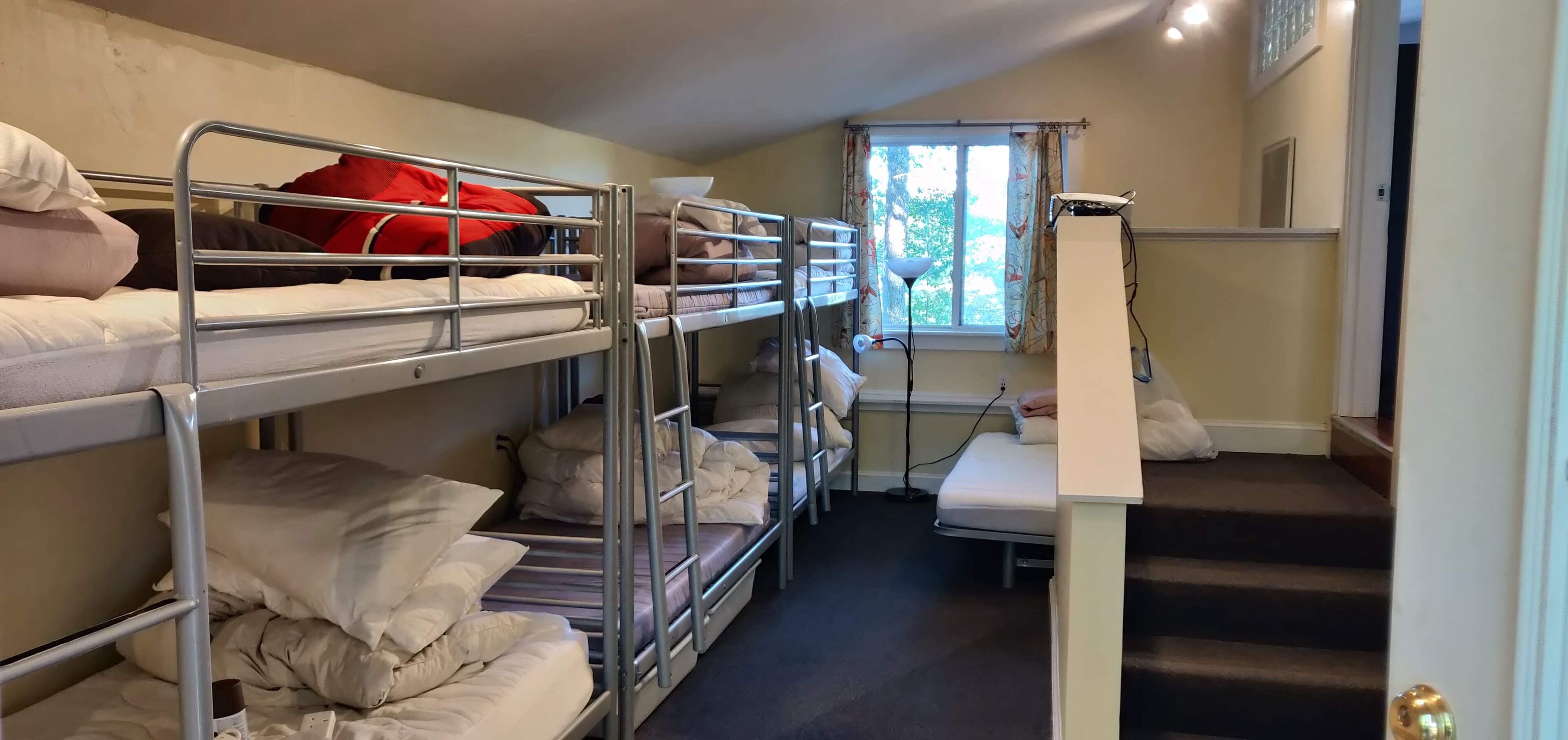 Une chambre de dortoir avec des lits superposés, un bureau et une fenêtre avec des rideaux.