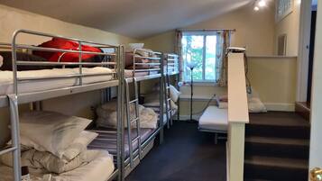 Une chambre de dortoir avec des lits superposés, un bureau et une fenêtre avec des rideaux.