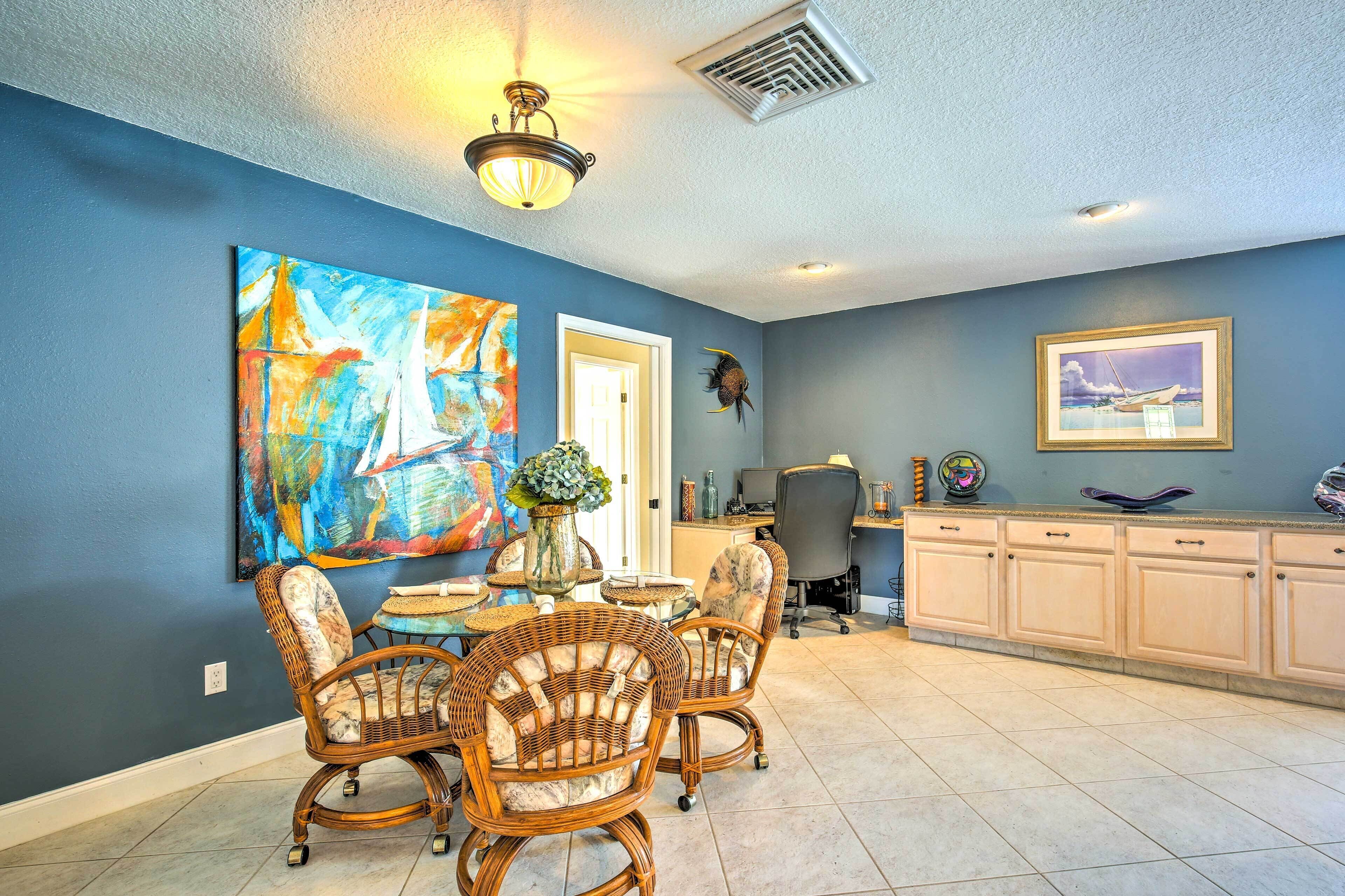 A dining area with wicker chairs, a table, and a vase of flowers.