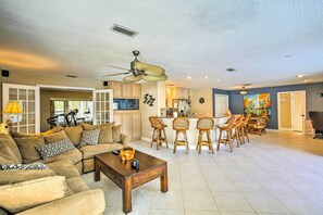 A spacious living room with a large sectional sofa, a coffee table, and a dining area with a kitchen in the background. - Solar-Heated Pool! Tropical Apollo Beach Hideaway (Apollo Beach)