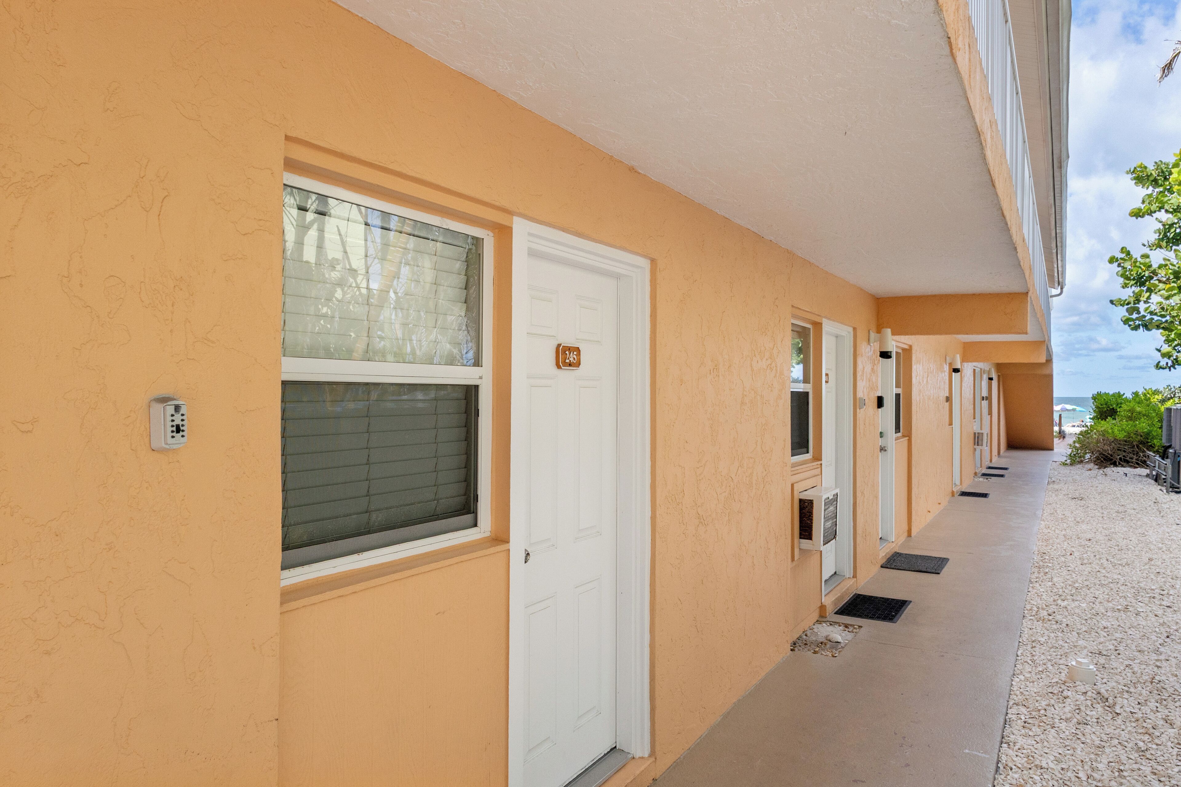 A row of hotel rooms with a beige exterior, white doors, and a small window with blinds.