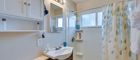 A bathroom with a white sink, vanity, and a shower curtain.