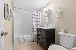 A bathroom with a bathtub, toilet, sink, and a mirror. - Sun, Sand & Silver Sands – Gulfside Resort #237 by RVA (Longboat Key)