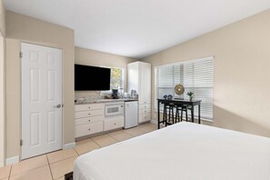 A bedroom with a bed, a kitchenette with a microwave, and a TV. - Sun, Sand & Silver Sands – Gulfside Resort #237 by RVA (Longboat Key)