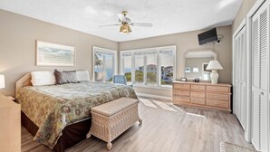Un dormitorio con cama, cómoda, televisor y ventana con vistas.