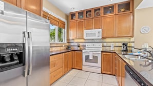 Una cocina moderna con electrodomésticos de acero inoxidable, armarios de madera y un salpicadero de azulejos.