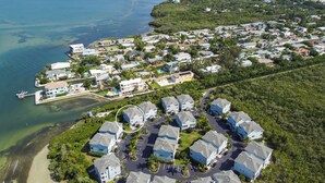 Vista aérea de una zona residencial costera con casas, un puerto deportivo y aguas azules cristalinas.