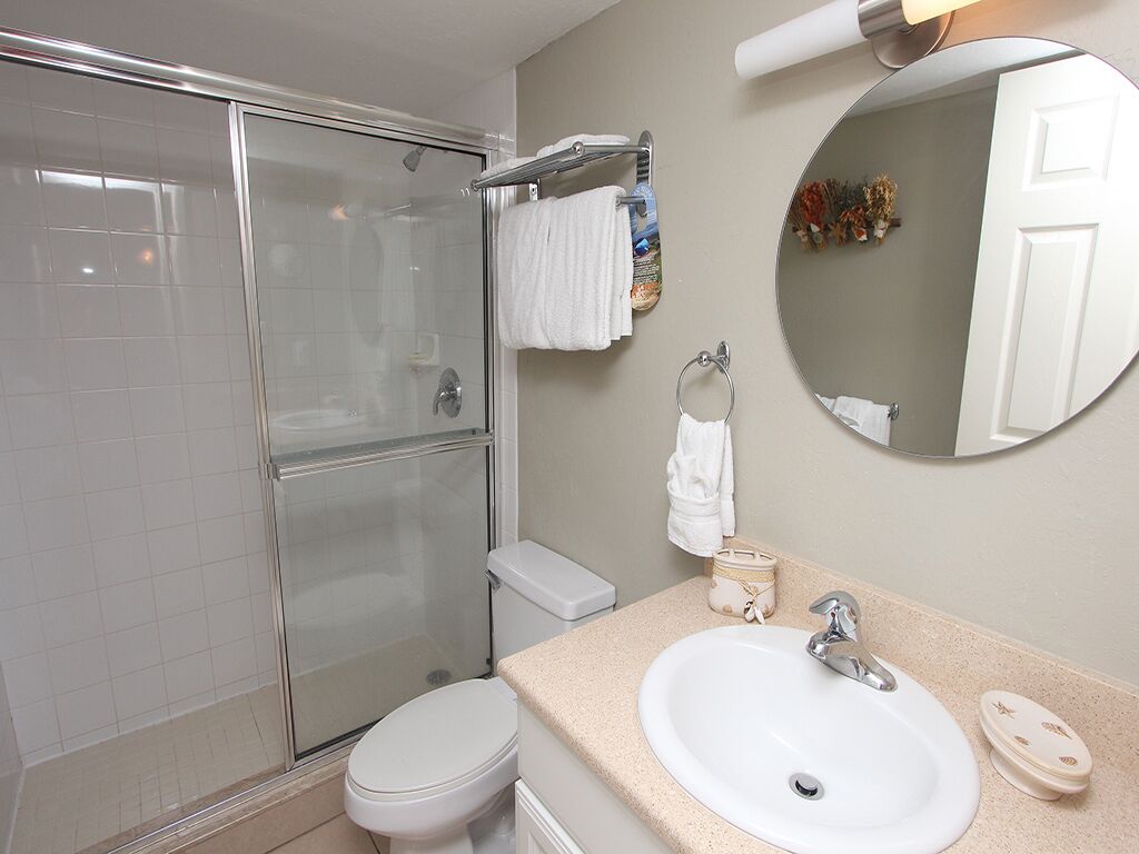 Une salle de bain avec une douche à parois de verre, des toilettes, un lavabo avec un miroir au-dessus et un porte-serviettes avec des serviettes.