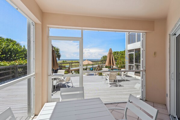 En balkon med havudsigt, hvide møbler og et poolområde.