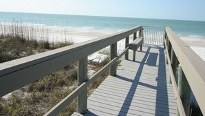 A wooden boardwalk leading to a beach with a bench and railing. - Coastal Serenity Sea Twig 102-Beachfront Condo w Private Lanai & Pool by RVA (Longboat Key)