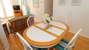 A dining area with a round wooden table, white chairs, and a vase with flowers. - Siesta Key Getaway – Pet Friendly & Steps to Beach: Siesta Bungalow by RVA (Sarasota)