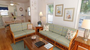 A cozy living room with a sofa set, a wooden coffee table, and a dining area with a chair and table. - Siesta Key Getaway – Pet Friendly & Steps to Beach: Siesta Bungalow by RVA (Sarasota)
