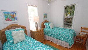 A bedroom with two beds, a nightstand, a chair, and artwork on the walls. - Siesta Key Getaway – Pet Friendly & Steps to Beach: Siesta Bungalow by RVA (Sarasota)