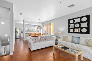 Relax in this stylish living room with a sofa, coffee table, and wall art, surrounded by a neutral color palette and natural light.