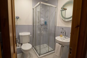 Une salle de bain avec une douche à parois de verre, des toilettes et un lavabo avec un miroir au-dessus.