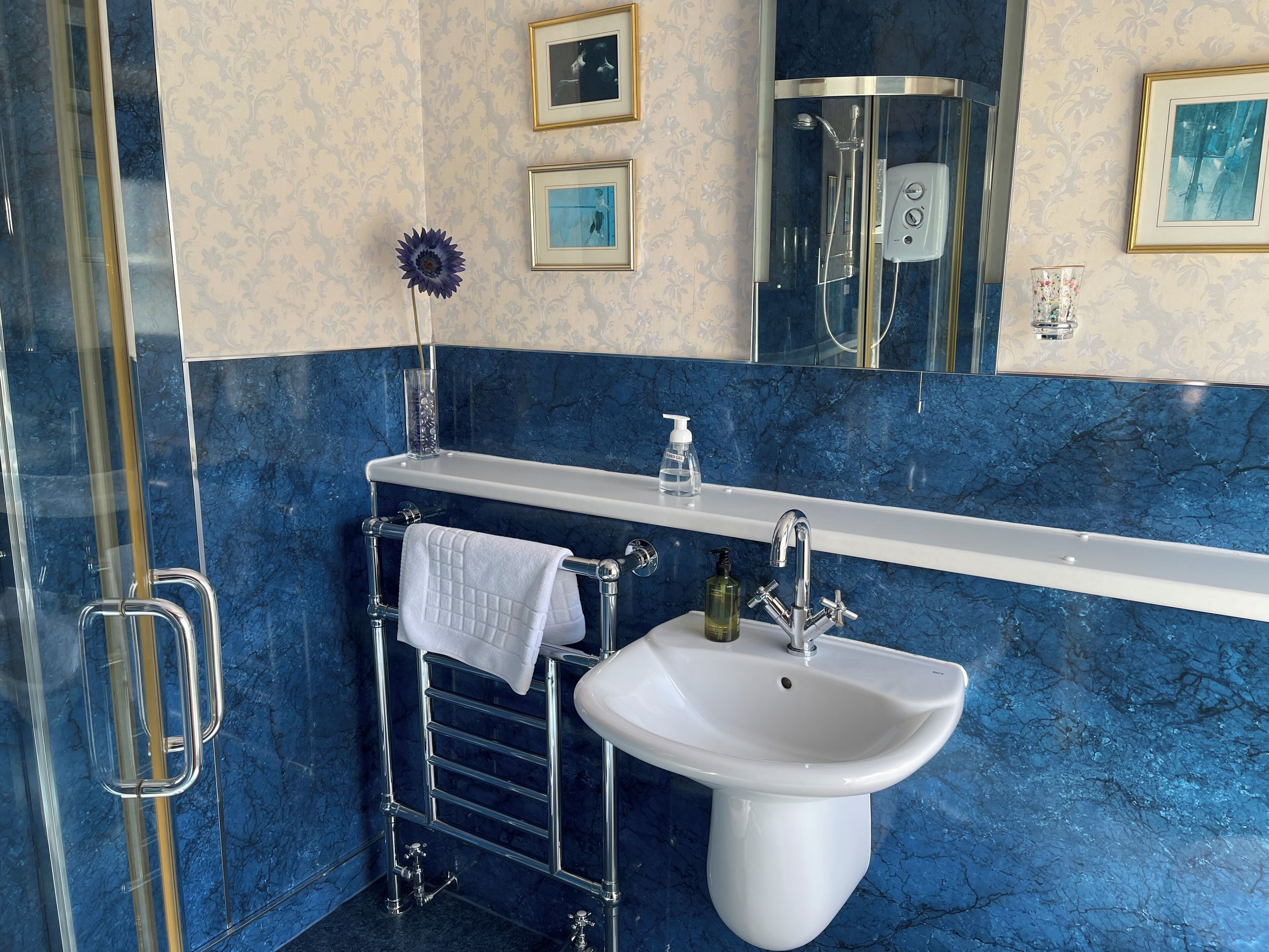 Une salle de bain avec un lavabo blanc, un porte-serviettes chromé et une cabine de douche.