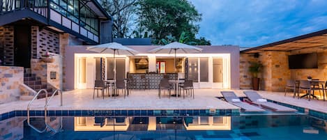 Una piscina al aire libre, sillones reclinables de piscina