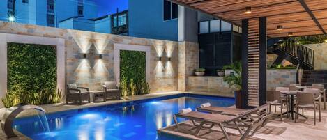 Una piscina al aire libre, sillones reclinables de piscina