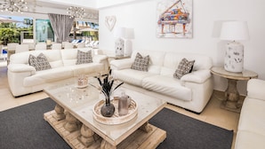 Ein stilvolles Wohnzimmer mit weißen Sofas, einem Glastisch und dekorativen Kissen.
